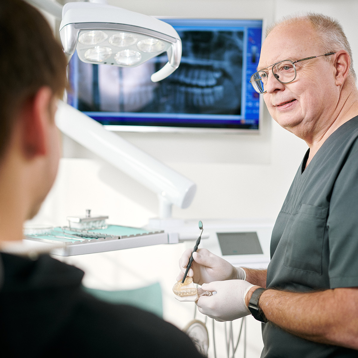 Zahnarzt Dentafamily Wiesentheid erklärt Behandlungsplan anhand eines Gebissmodells für optimale Mundgesundheit.